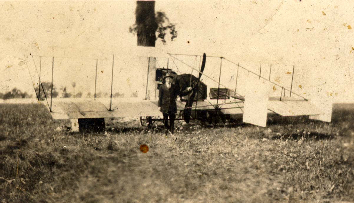 an%20unidentified%20man%20standing%20in%20front%20of%20a%20biplane